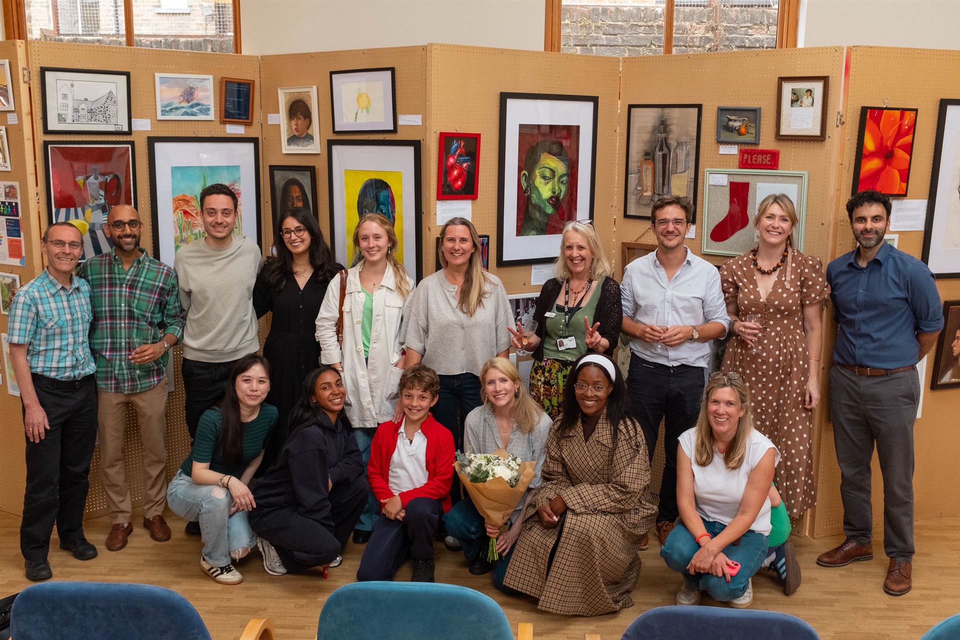 Group of contributing members standing in front of art exhibition