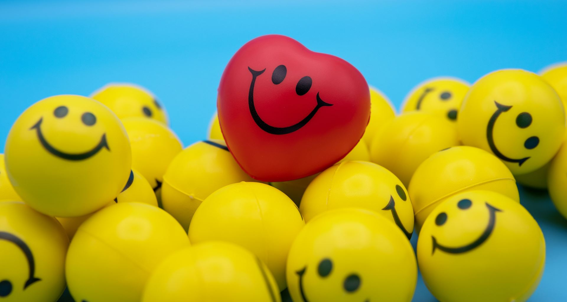smiles on yellow balls with smile on red heart, blue background