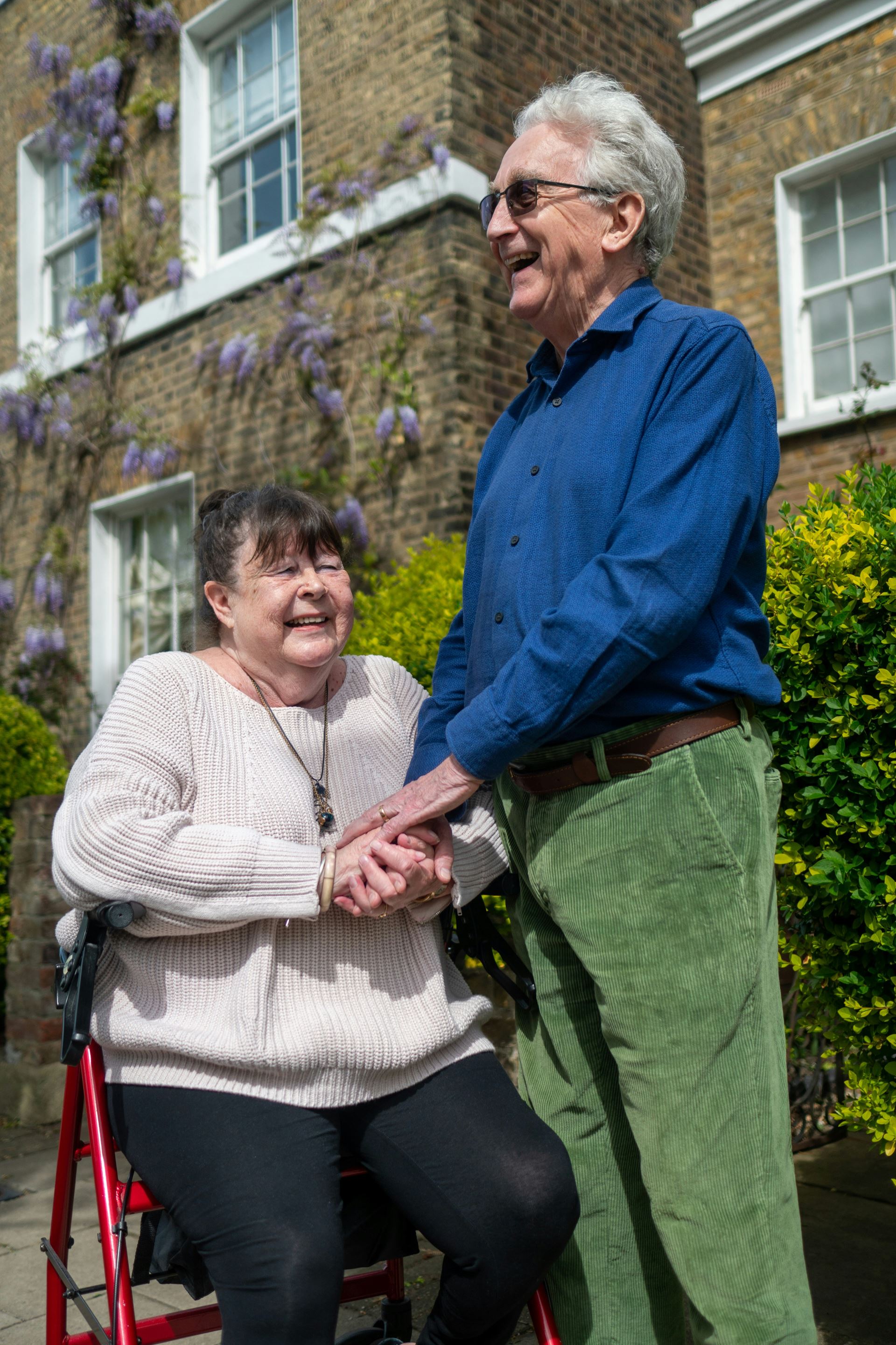 carer standing over a smiling lady in a wheelchair